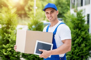 Genç teslimatçı elinde bir karton kutu tutuyor.