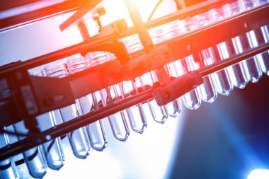 Modern içecek fabrikasında otomatik doldurma makinesi plastik PET şişelerine su doldurur.