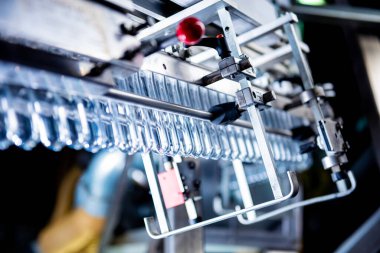 Modern içecek fabrikasında otomatik doldurma makinesi plastik PET şişelerine su doldurur.