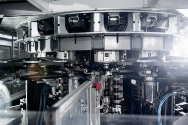 Modern içecek fabrikasında otomatik doldurma makinesi plastik PET şişelerine su doldurur.