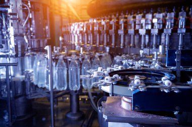 Modern içecek fabrikasında otomatik doldurma makinesi plastik PET şişelerine su doldurur.