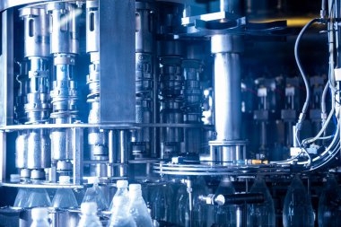 Modern içecek fabrikasında otomatik doldurma makinesi plastik PET şişelerine su doldurur.