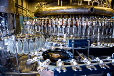 Modern içecek fabrikasında otomatik doldurma makinesi plastik PET şişelerine su doldurur.