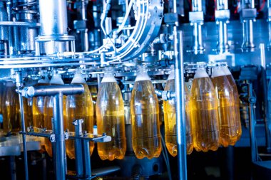 Modern içecek fabrikasında otomatik doldurma makinesi plastik PET şişelerine su doldurur.