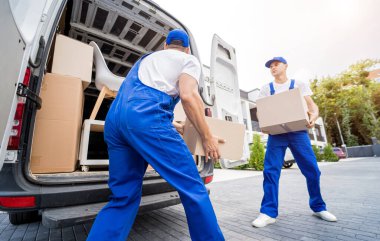 İki nakliye şirketi çalışanı bir minibüse kutu ve mobilya yüklüyorlar..