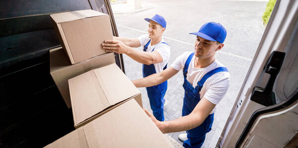 Two removal company workers unloading boxes from minibus