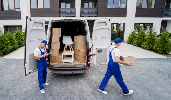 Two removal company workers unloading boxes and furniture from minibus — Stock Photo, Image