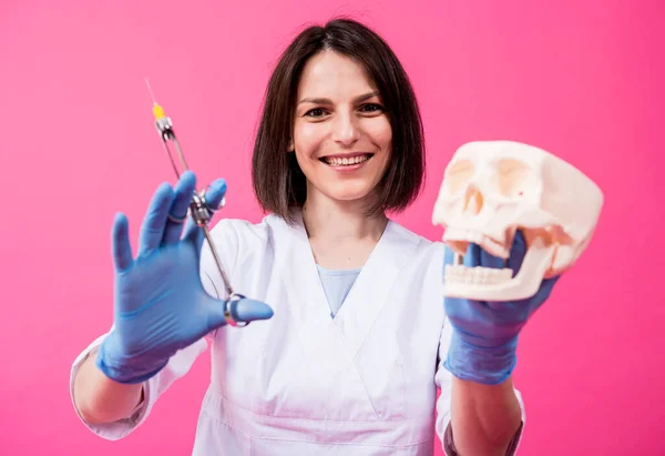 Kvinde tandlæge med en carpool sprøjte injicerer bedøvelse i tyggegummi af den kunstige kranium - Stock-foto