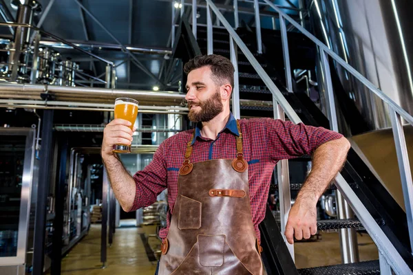 Jonge mannelijke brouwer in lederen schort in moderne brouwerij fabriek — Stockfoto