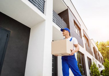 Genç teslimatçı elinde bir karton kutu tutuyor.