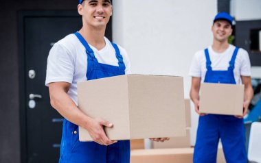 İki nakliye şirketi çalışanı bir minibüse kutu yüklüyorlar..