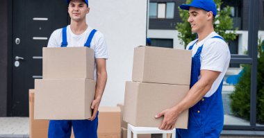 İki nakliye şirketi çalışanı bir minibüse kutu yüklüyorlar..