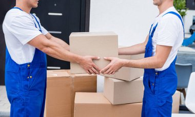 İki nakliye şirketi çalışanı bir minibüse kutu yüklüyorlar..