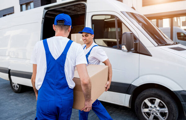 Two removal company workers are loading boxes into a minibus.