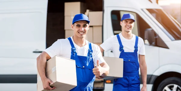 Dos trabajadores de la empresa de mudanzas descargan cajas de minibús en un nuevo hogar —  Fotos de Stock