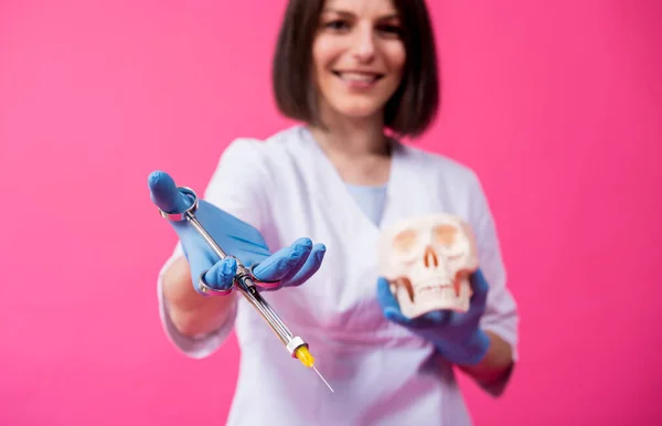 Woman dentist with a carpool syringe injects anesthetic into the gum of the artificial skull — Stock Photo, Image