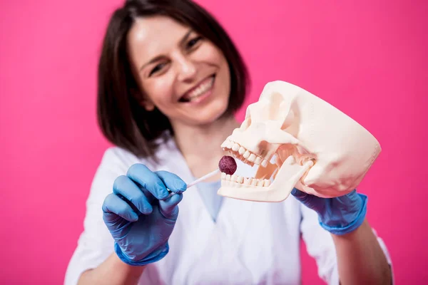 Beautiful girl proposes lollipop for artificial skull — Stock Photo, Image