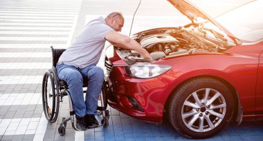 Tekerlekli sandalyedeki engelli adam, arabasını park yerinde kontrol et.