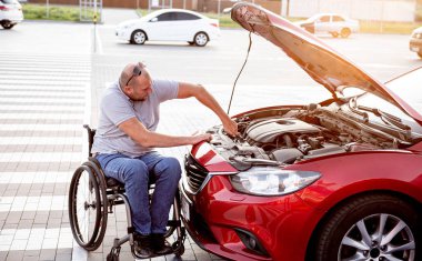 Tekerlekli sandalyedeki engelli adam, arabasını park yerinde kontrol et.