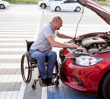 Tekerlekli sandalyedeki engelli adam, arabasını park yerinde kontrol et.