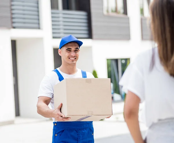 Young courier delivering goods to a young woman at home