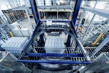 İçecek fabrikasında ambalaj hattı için modern bağlama ve taşıma makinesi.