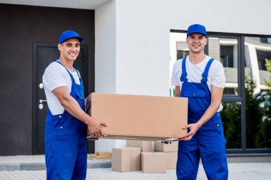 İki nakliye şirketi çalışanı minibüsten yeni eve kutular boşaltıyor.