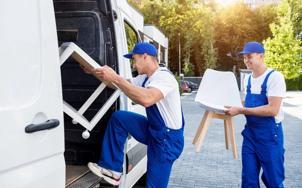 Due operai dell'azienda di trasloco stanno caricando scatole e mobili in un minibus. — Foto Stock