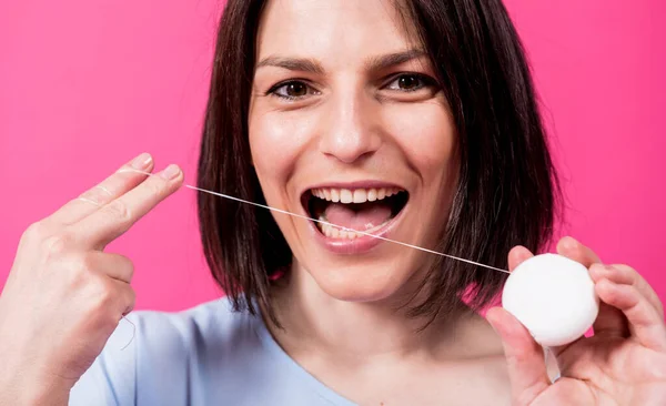 Schöne junge Frau verwenden Zahnseide auf rosa Hintergrund — Stockfoto