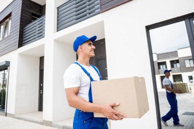 Genç teslimatçı elinde bir karton kutu tutuyor.