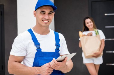 Genç kurye evde genç bir bayana mal getiriyor.