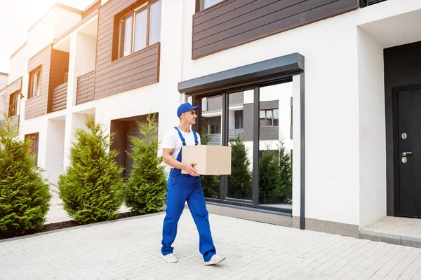 Genç teslimatçı elinde bir karton kutu tutuyor.