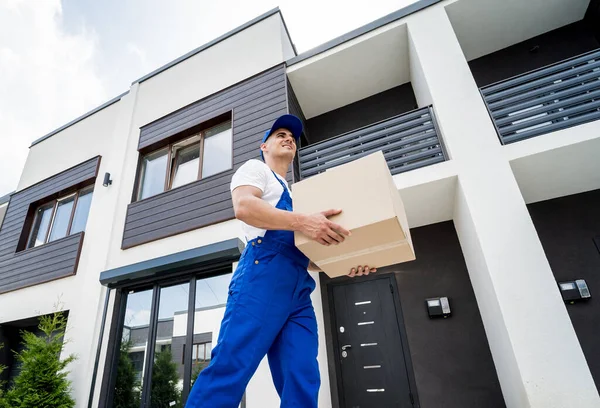 Junger Zusteller hält einen Karton in der Hand — Stockfoto