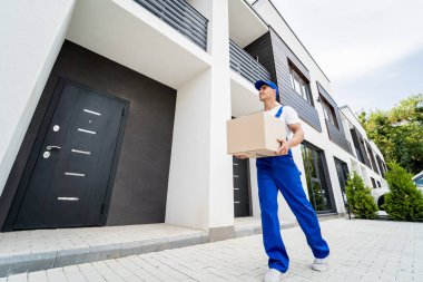 Genç teslimatçı elinde bir karton kutu tutuyor.
