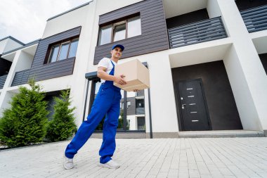 Genç teslimatçı elinde bir karton kutu tutuyor.