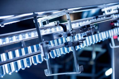 Modern içecek fabrikasında otomatik doldurma makinesi plastik PET şişelerine su doldurur.