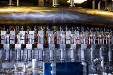 Modern içecek fabrikasında otomatik doldurma makinesi plastik PET şişelerine su doldurur.