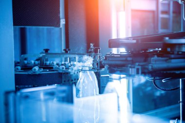 Modern içecek fabrikasında otomatik doldurma makinesi plastik PET şişelerine su doldurur.