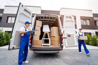 İki nakliye şirketi çalışanı bir minibüse kutu ve mobilya yüklüyorlar..