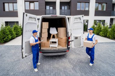 İki nakliye şirketi çalışanı bir minibüse kutu ve mobilya yüklüyorlar..