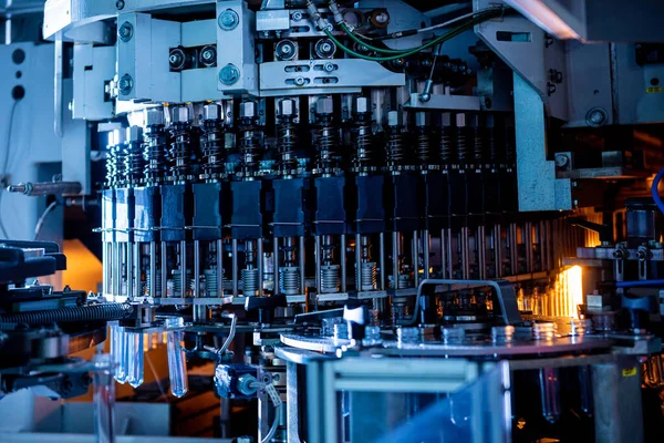 Máquina de enchimento automático derrama água em garrafas PET de plástico na moderna fábrica de bebidas. — Fotografia de Stock