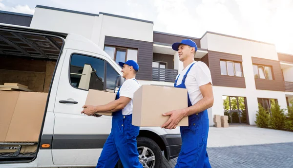 Zwei Mitarbeiter einer Umzugsfirma laden Kisten und Möbel in einen Kleinbus. — Stockfoto