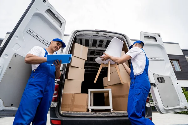 Dos trabajadores de la empresa de mudanzas que descargan cajas y muebles del minibús —  Fotos de Stock