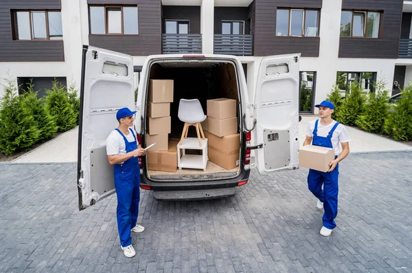 Zwei Mitarbeiter einer Umzugsfirma laden Kisten und Möbel in einen Kleinbus. — Stockfoto