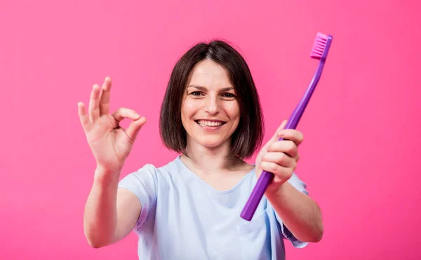 Schöne glückliche junge Frau mit großer Zahnbürste auf leerem rosa Hintergrund — Stockfoto