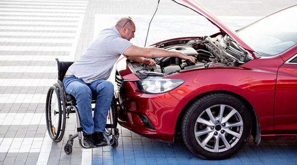 Tekerlekli sandalyedeki engelli adam, arabasını park yerinde kontrol et.