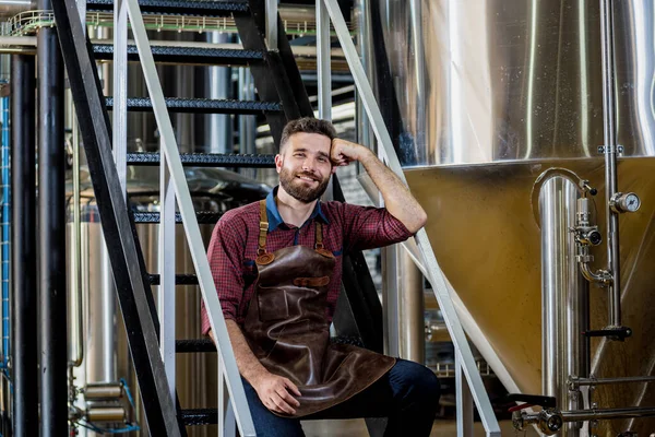 Jonge mannelijke brouwer in lederen schort in moderne brouwerij fabriek — Stockfoto