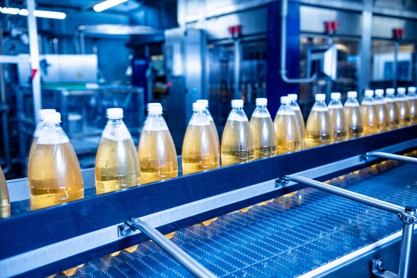 Transportband met flessen voor sap of water in een moderne drankfabriek — Stockfoto