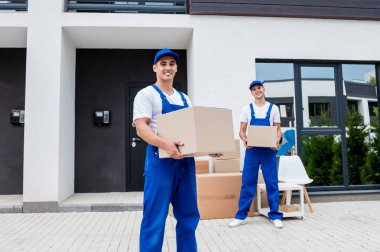 İki nakliye şirketi çalışanı bir minibüse kutu yüklüyorlar..