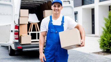 Taşıma şirketi çalışanı minibüsten müşterilerin evlerine kutu indiriyor.